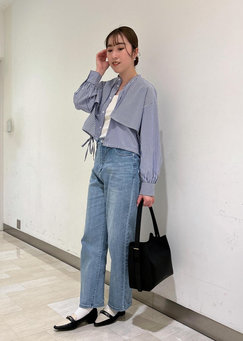 ブラック系のショルダーバッグ、ブルー系のシャツ/ブラウス、ブルー系のデニムパンツを着用したレディースの春コーディネートの3枚目の写真