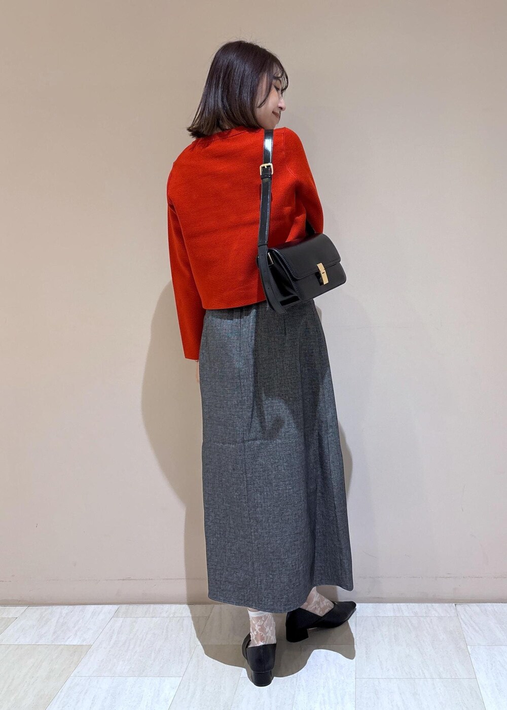 ブラック系のショルダーバッグ、グレー系のスカート、ブラック系のパンプスを着用したレディースの秋コーディネートの9枚目の写真