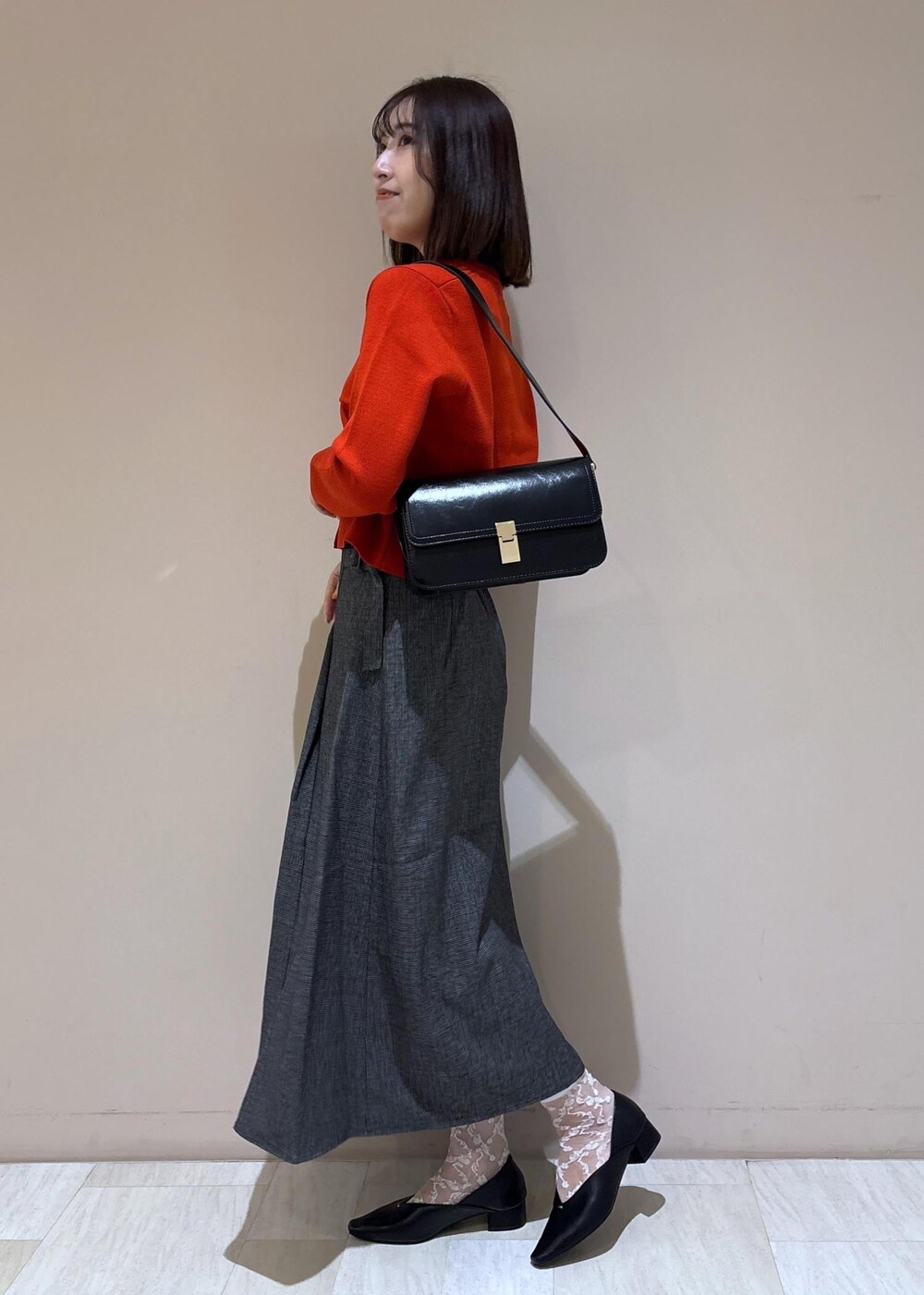 ブラック系のショルダーバッグ、グレー系のスカート、ブラック系のパンプスを着用したレディースの秋コーディネートの4枚目の写真