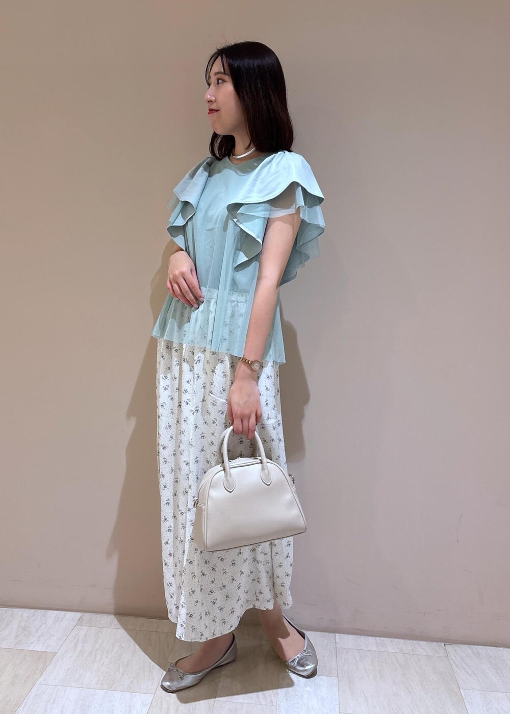 ベージュ系のボストンバッグ、シルバー系のバレエシューズ、ホワイト系のスカートを着用したレディースの夏コーディネートの2枚目の写真