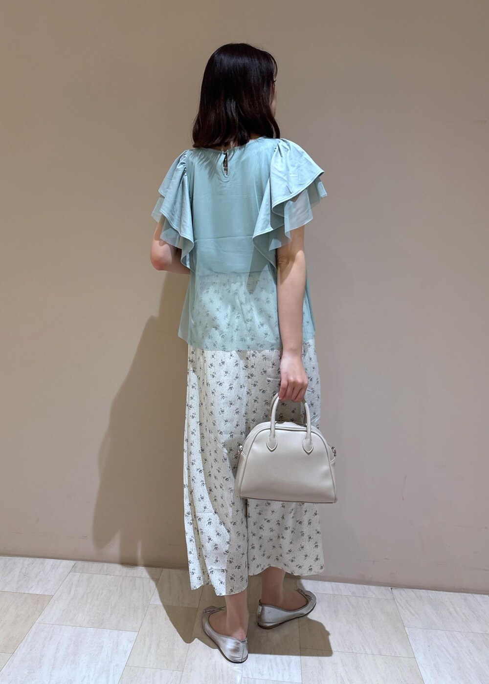 ベージュ系のボストンバッグ、シルバー系のバレエシューズ、ホワイト系のスカートを着用したレディースの夏コーディネートの6枚目の写真