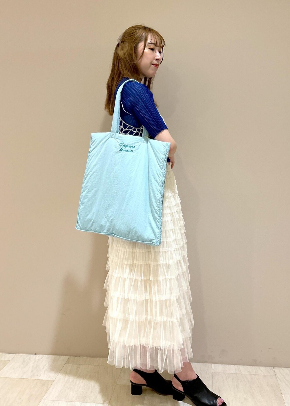 ブルー系のトートバッグ、ブラック系のサンダル、ブルー系のTシャツ/カットソーを着用したレディースの夏コーディネートの5枚目の写真