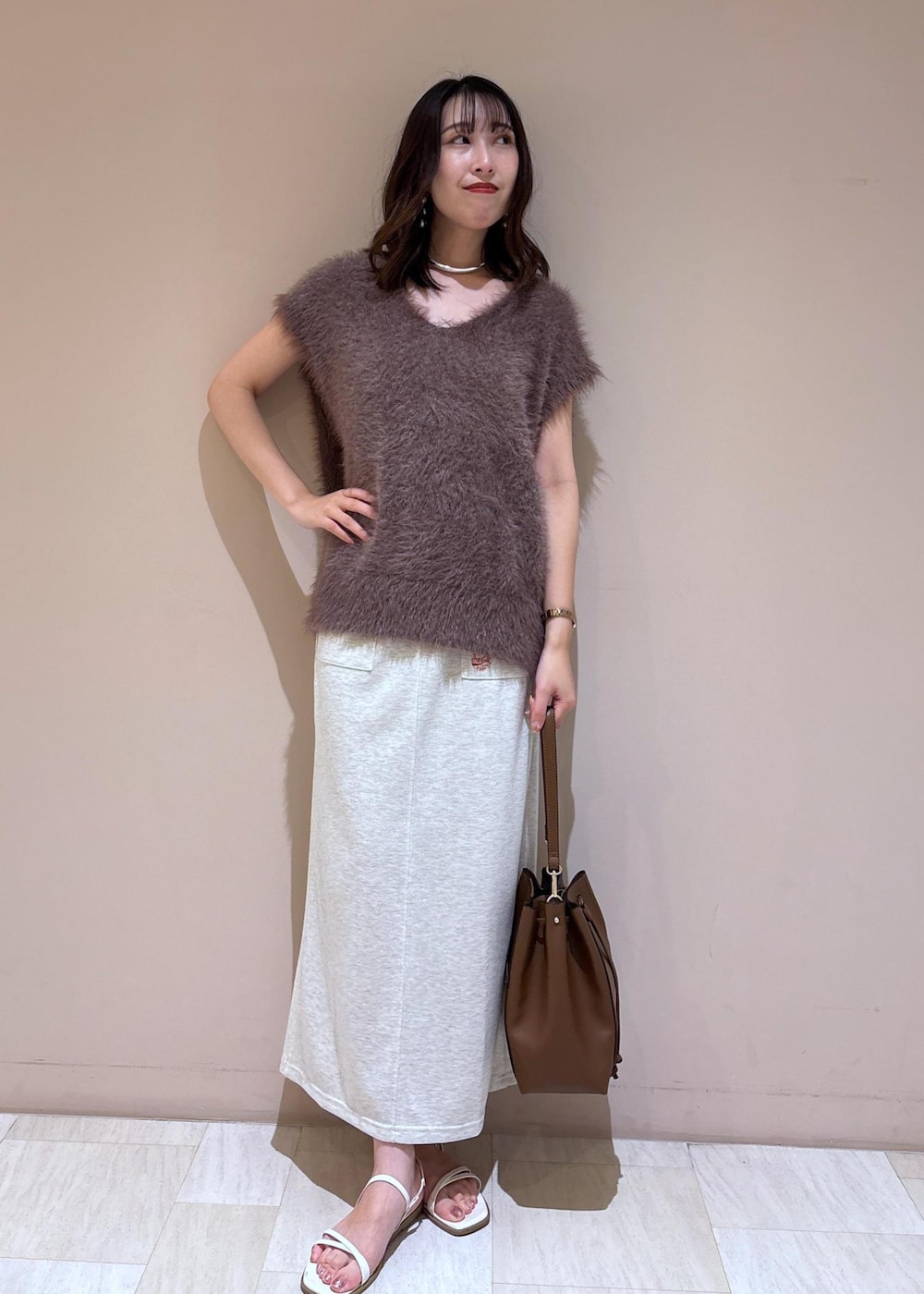 ブラウン系のショルダーバッグ、ブラウン系のベスト、グレー系のスカートを着用したレディースの夏コーディネートの3枚目の写真