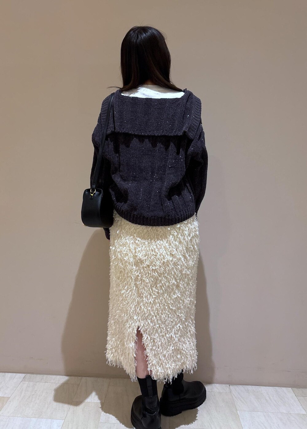 ホワイト系のスカート、ホワイト系のTシャツ/カットソー、グレー系のニット/セーターを着用したレディースの冬コーディネートの4枚目の写真