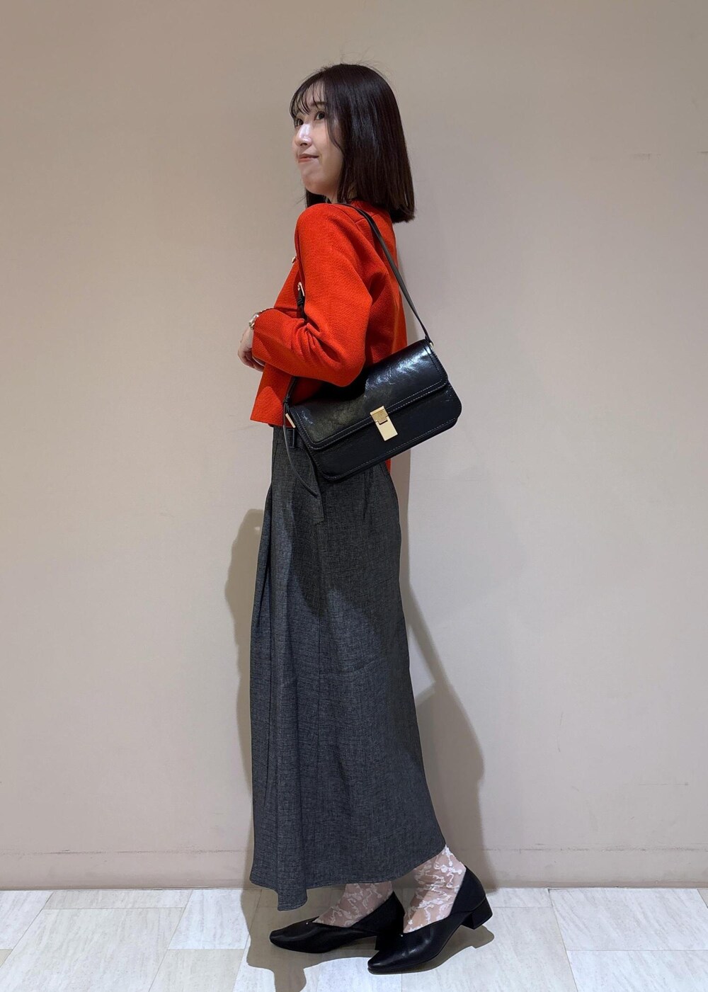 ブラック系のショルダーバッグ、グレー系のスカート、ブラック系のパンプスを着用したレディースの秋コーディネートの3枚目の写真