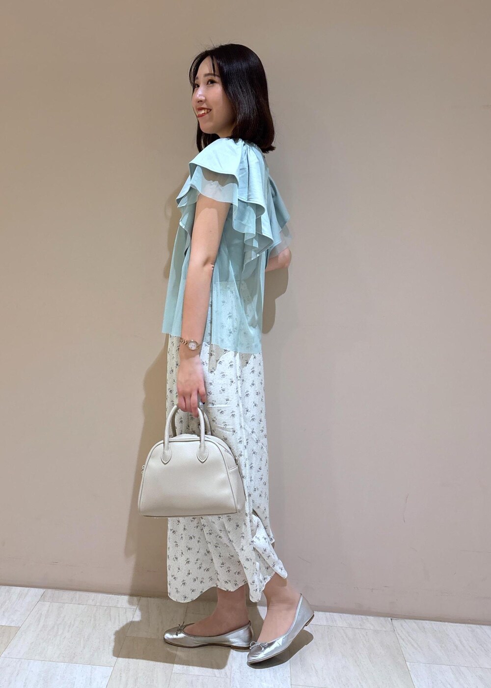 ベージュ系のボストンバッグ、シルバー系のバレエシューズ、ホワイト系のスカートを着用したレディースの夏コーディネートの3枚目の写真