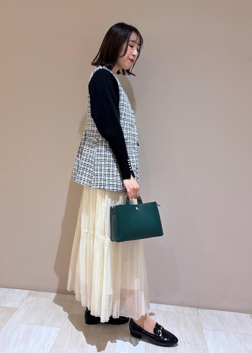 ホワイト系のスカート、グリーン系のショルダーバッグ、ブラック系のニット/セーターを着用したレディースの冬コーディネートの5枚目の写真