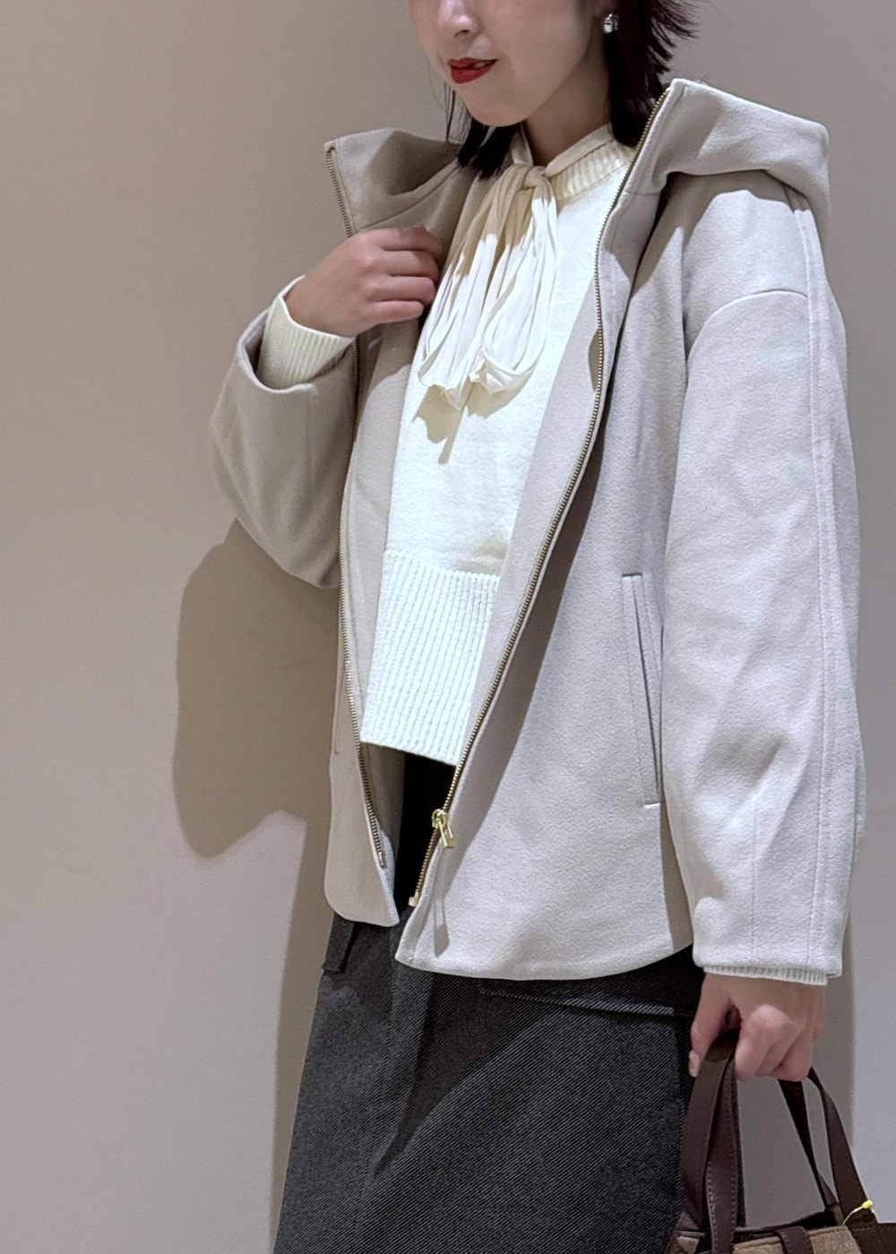 ホワイト系のニット/セーター、ホワイト系のシャツ/ブラウス、ブラウン系のトートバッグを着用したレディースの秋コーディネートの9枚目の写真