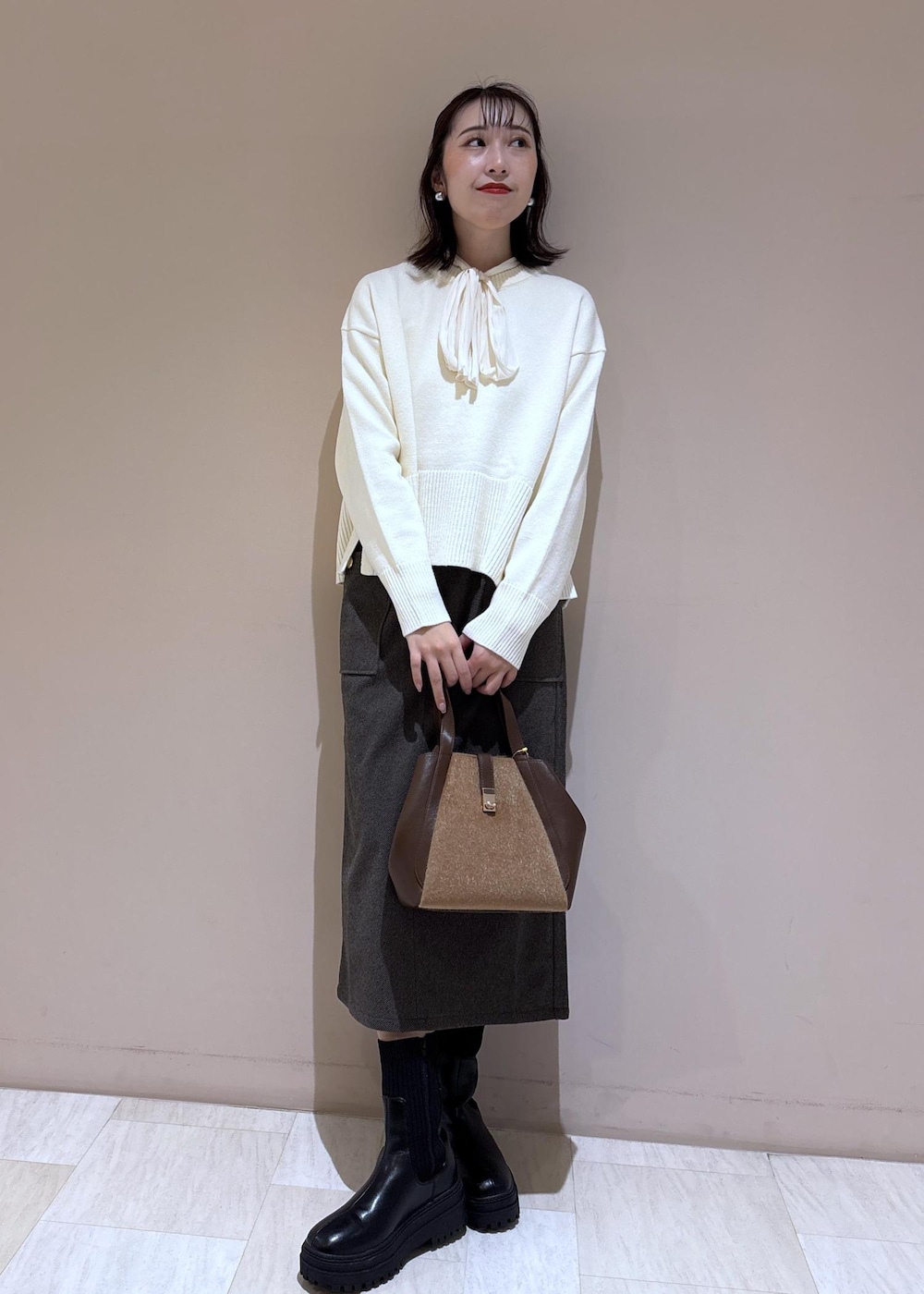ホワイト系のニット/セーター、ホワイト系のシャツ/ブラウス、ブラウン系のトートバッグを着用したレディースの秋コーディネートの4枚目の写真
