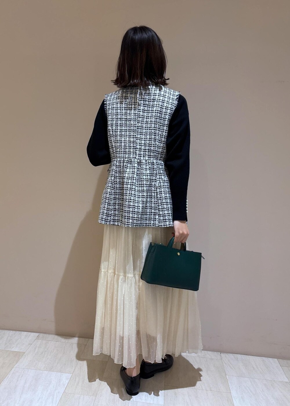 ホワイト系のスカート、グリーン系のショルダーバッグ、ブラック系のニット/セーターを着用したレディースの冬コーディネートの3枚目の写真