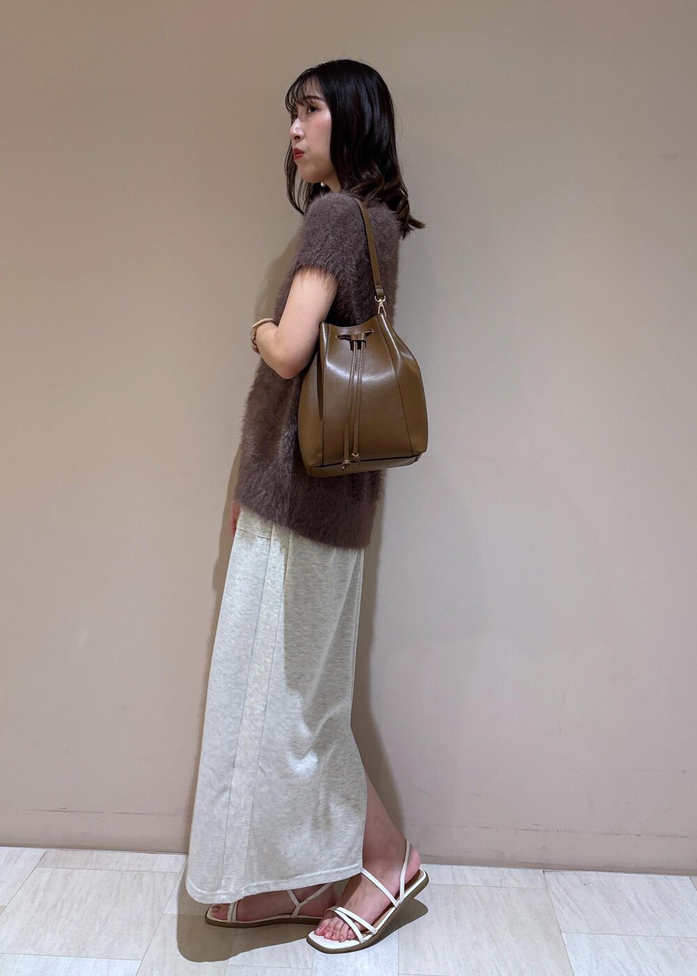 ブラウン系のショルダーバッグ、ブラウン系のベスト、グレー系のスカートを着用したレディースの夏コーディネートの4枚目の写真