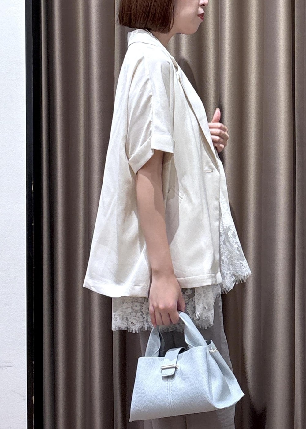 グレー系のその他パンツ、ブルー系のショルダーバッグ、ホワイト系のテーラードジャケットを着用したレディースの春コーディネートの7枚目の写真