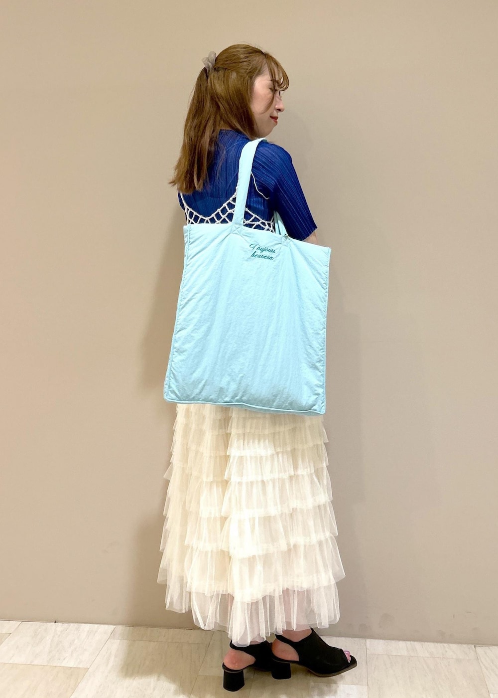 ブルー系のトートバッグ、ブラック系のサンダル、ブルー系のTシャツ/カットソーを着用したレディースの夏コーディネートの4枚目の写真