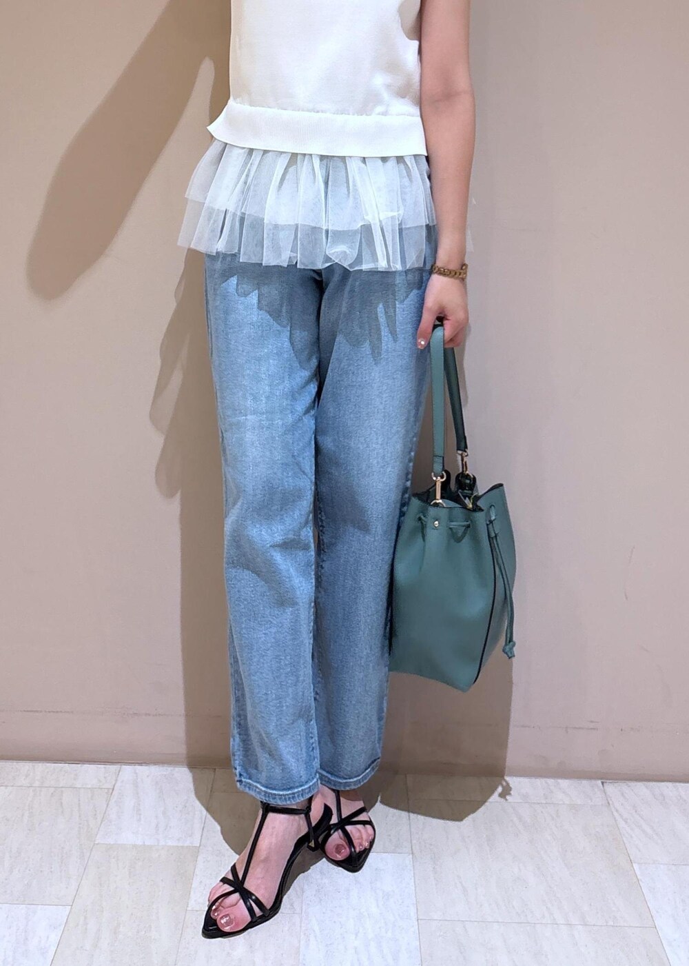 ブルー系のデニムパンツ、ブルー系のショルダーバッグ、ホワイト系のニット/セーターを着用したレディースの夏コーディネートの4枚目の写真