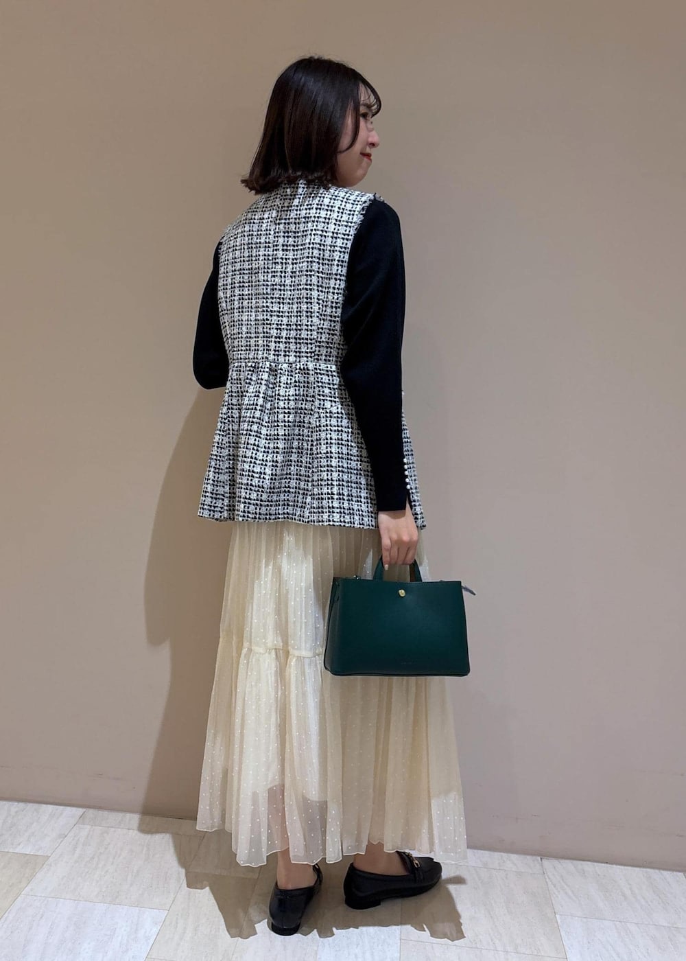 ホワイト系のスカート、グリーン系のショルダーバッグ、ブラック系のニット/セーターを着用したレディースの冬コーディネートの4枚目の写真
