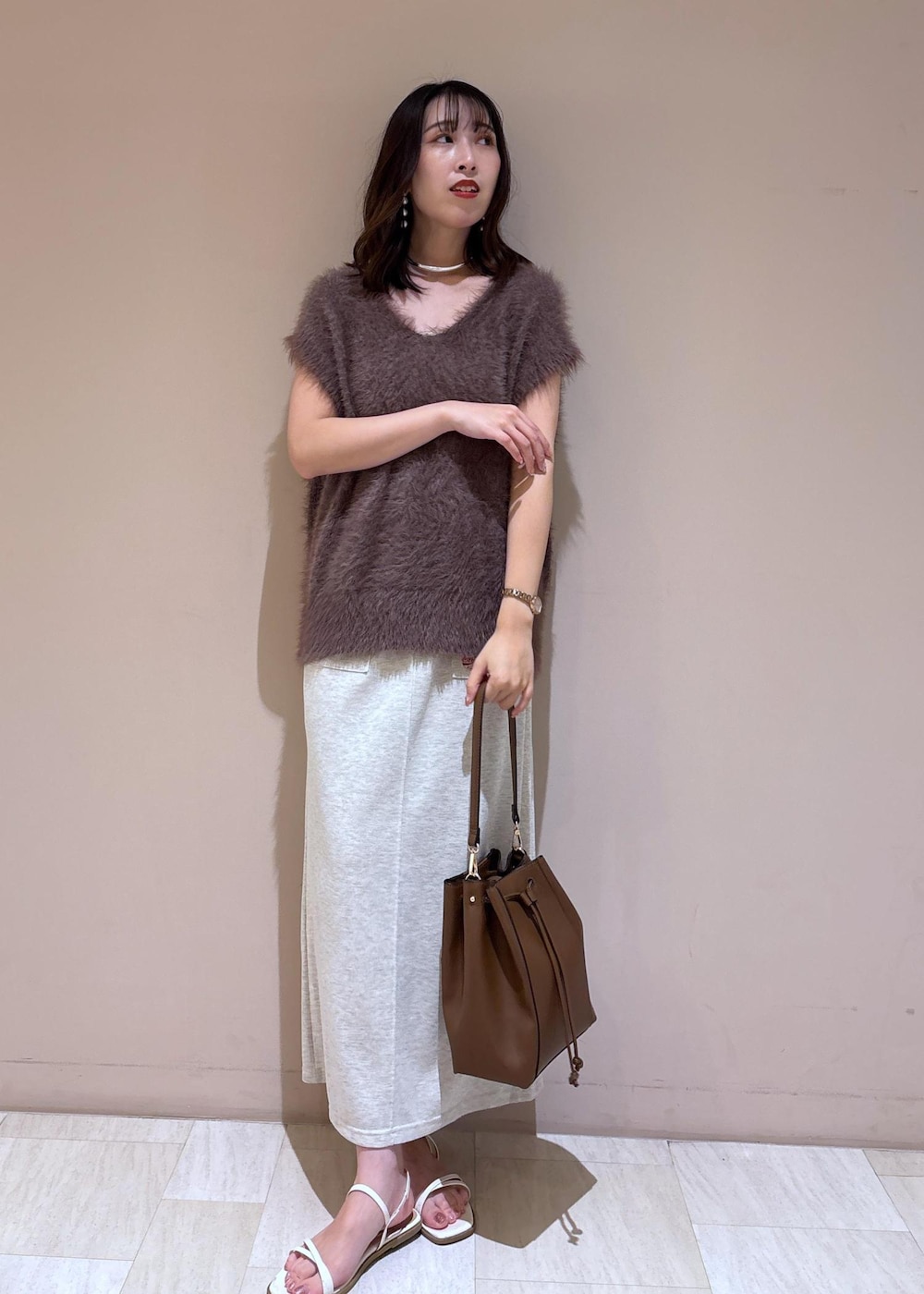 ブラウン系のショルダーバッグ、ブラウン系のベスト、グレー系のスカートを着用したレディースの夏コーディネートの2枚目の写真