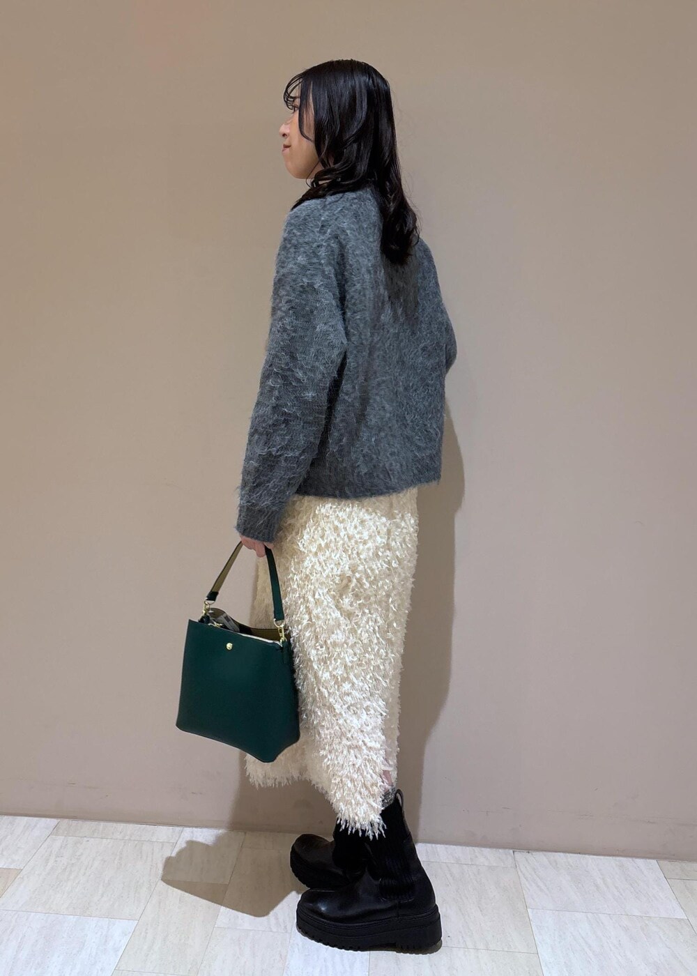 ホワイト系のスカート、グレー系のニット/セーターを着用したレディースの冬コーディネートの2枚目の写真