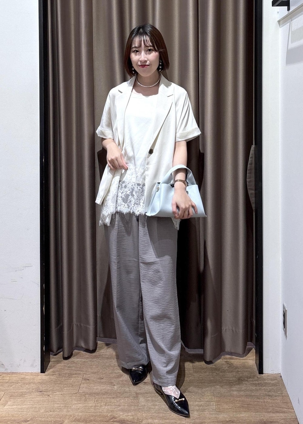 グレー系のその他パンツ、ブルー系のショルダーバッグ、ホワイト系のテーラードジャケットを着用したレディースの春コーディネートの2枚目の写真