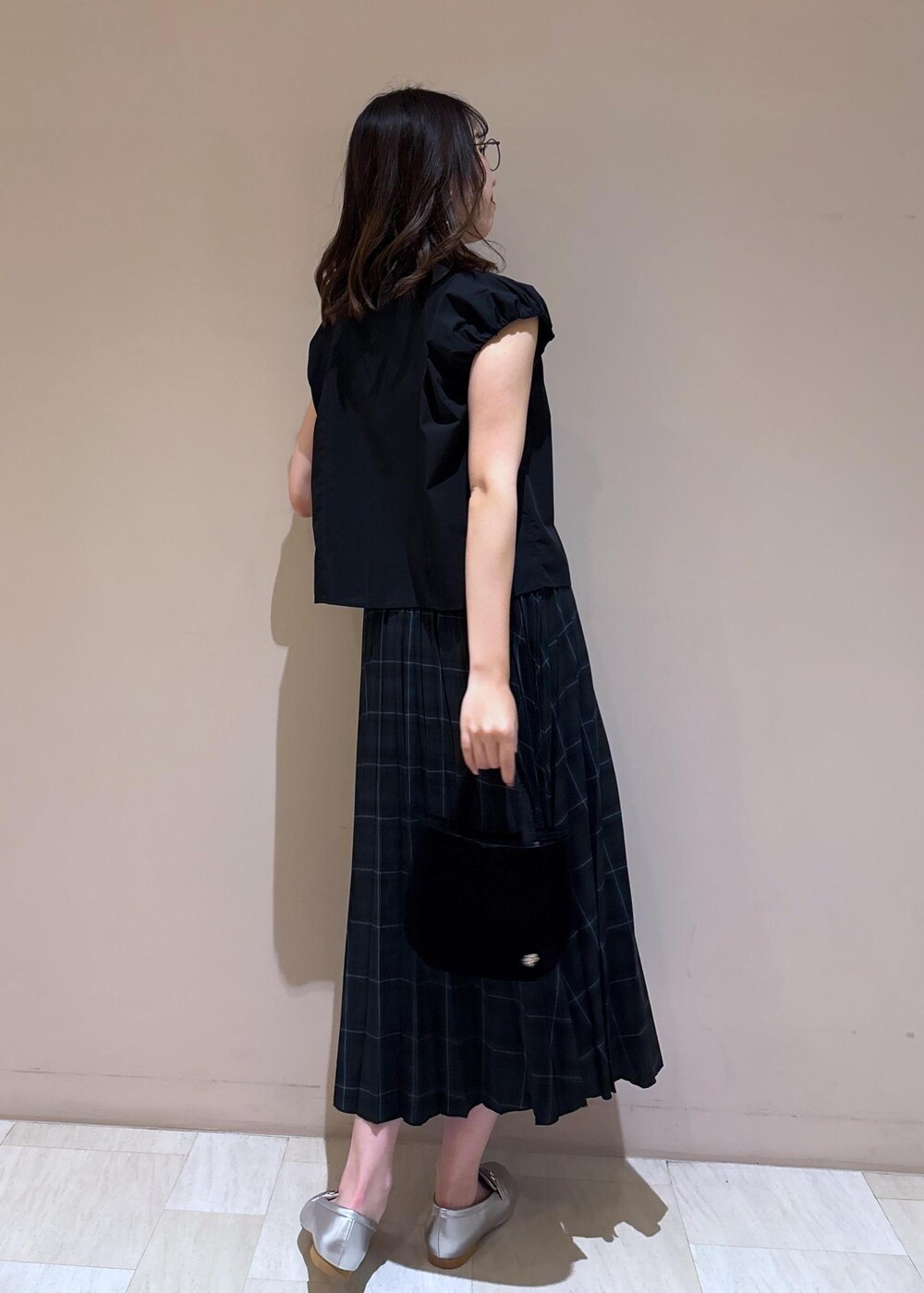 グリーン系のスカート、ブラック系のシャツ/ブラウス、シルバー系のローファーを着用したレディースの夏コーディネートの8枚目の写真