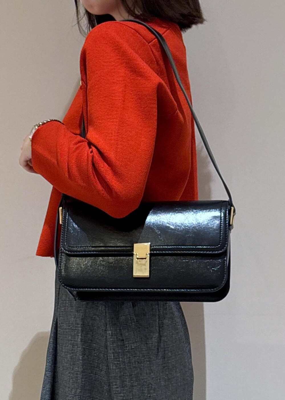 ブラック系のショルダーバッグ、グレー系のスカート、ブラック系のパンプスを着用したレディースの秋コーディネートの7枚目の写真