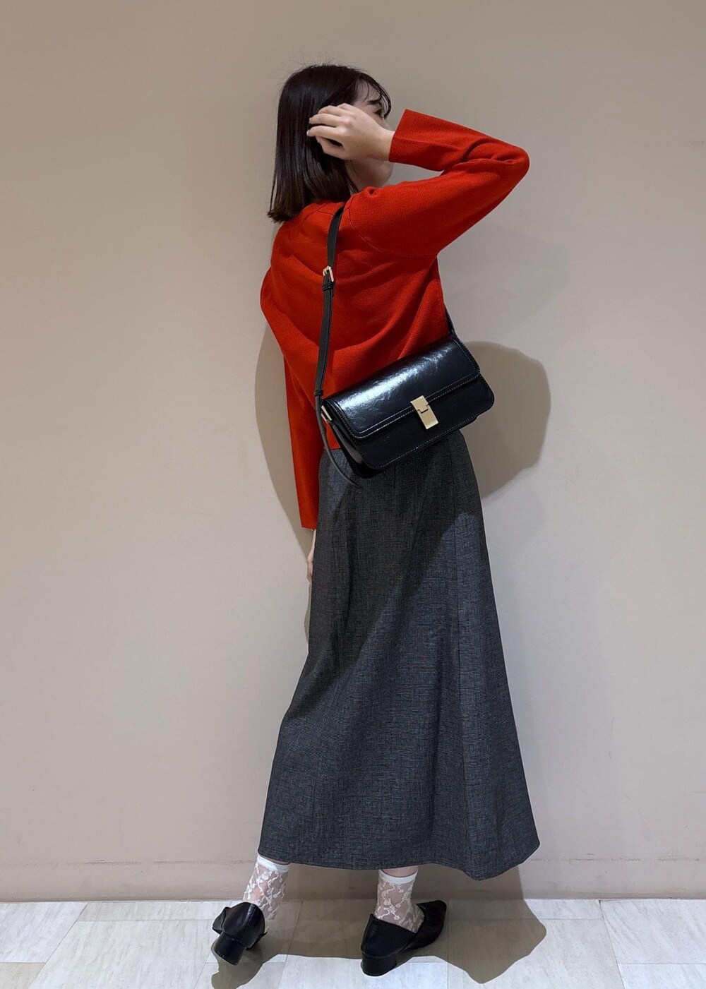 ブラック系のショルダーバッグ、グレー系のスカート、ブラック系のパンプスを着用したレディースの秋コーディネートの10枚目の写真