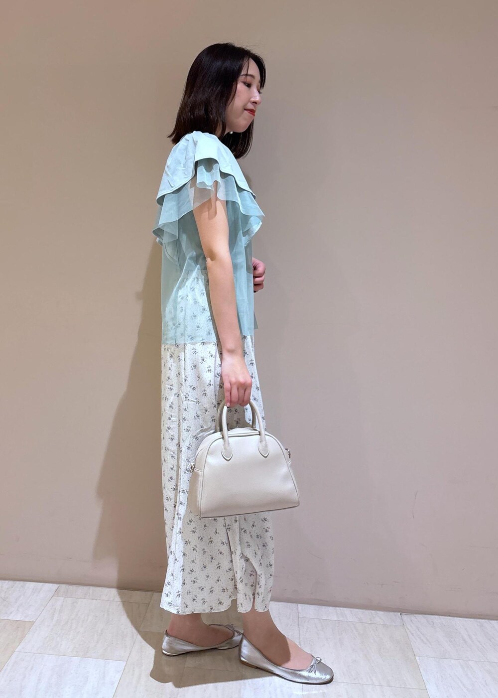 ベージュ系のボストンバッグ、シルバー系のバレエシューズ、ホワイト系のスカートを着用したレディースの夏コーディネートの7枚目の写真