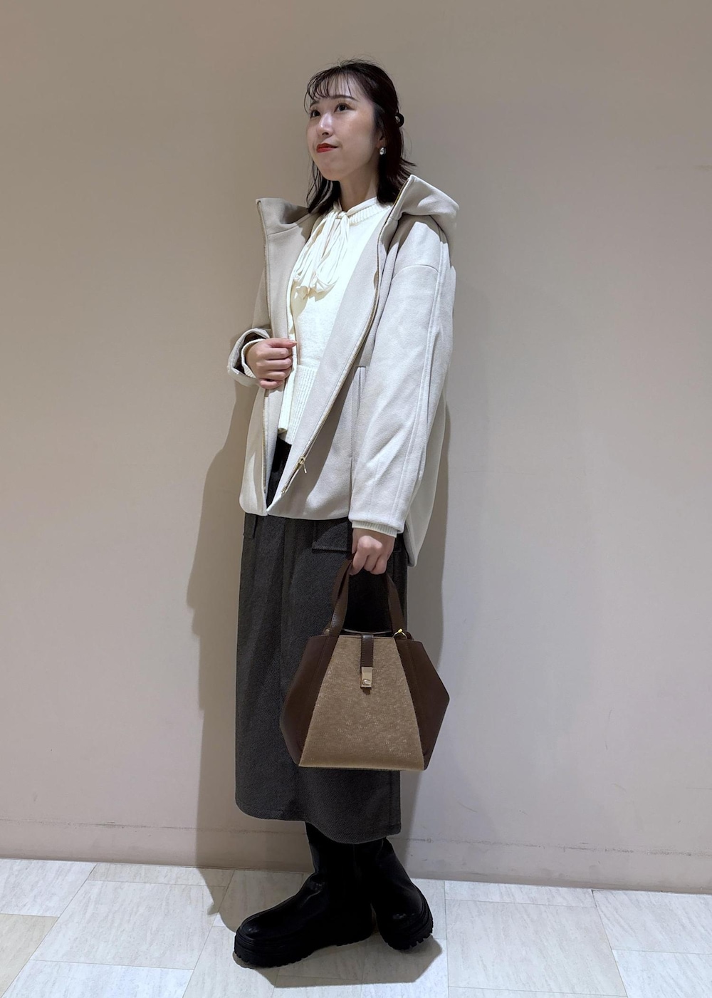 ホワイト系のニット/セーター、ホワイト系のシャツ/ブラウス、ブラウン系のトートバッグを着用したレディースの秋コーディネートの2枚目の写真