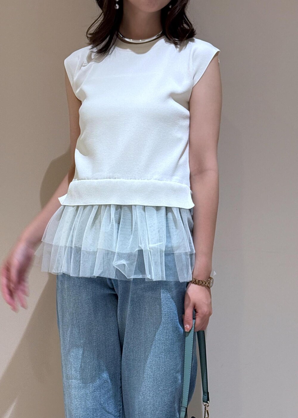 ブルー系のデニムパンツ、ブルー系のショルダーバッグ、ホワイト系のニット/セーターを着用したレディースの夏コーディネートの6枚目の写真