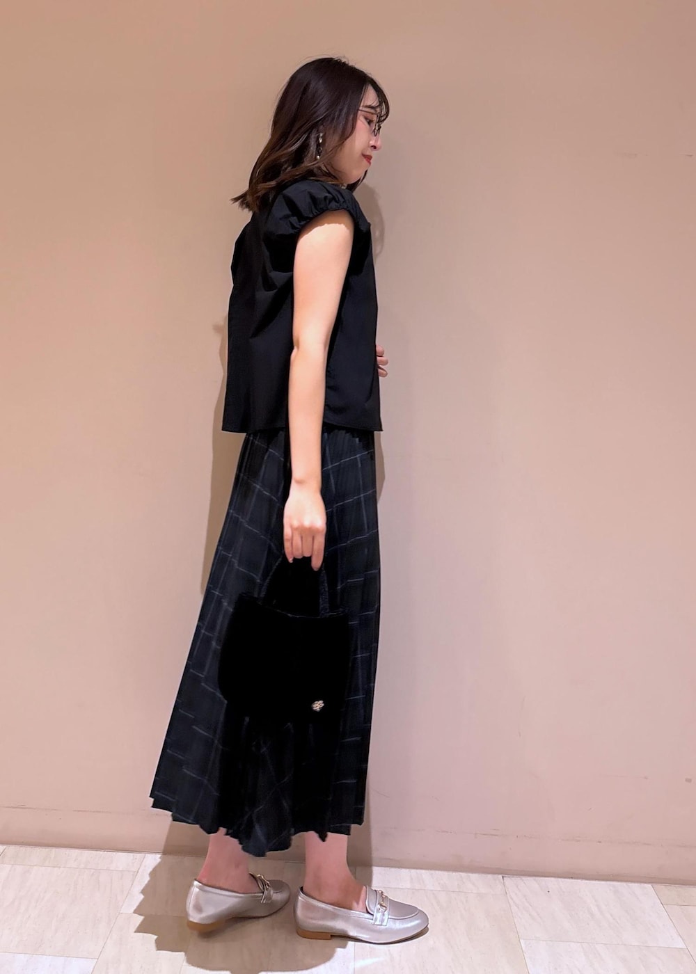 グリーン系のスカート、ブラック系のシャツ/ブラウス、シルバー系のローファーを着用したレディースの夏コーディネートの9枚目の写真