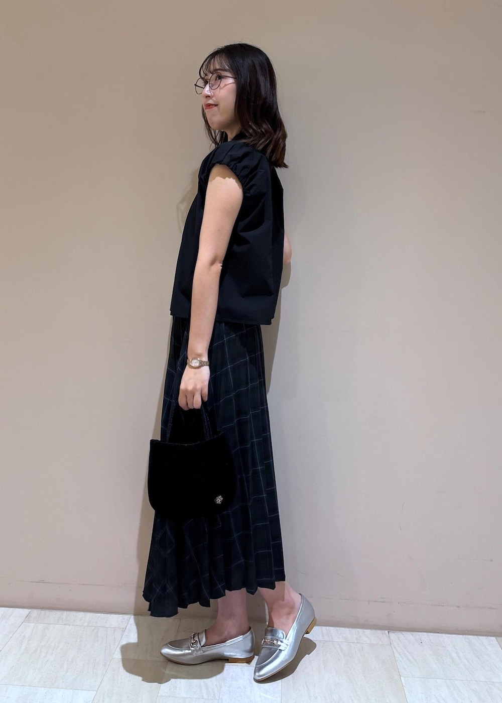 グリーン系のスカート、ブラック系のシャツ/ブラウス、シルバー系のローファーを着用したレディースの夏コーディネートの3枚目の写真