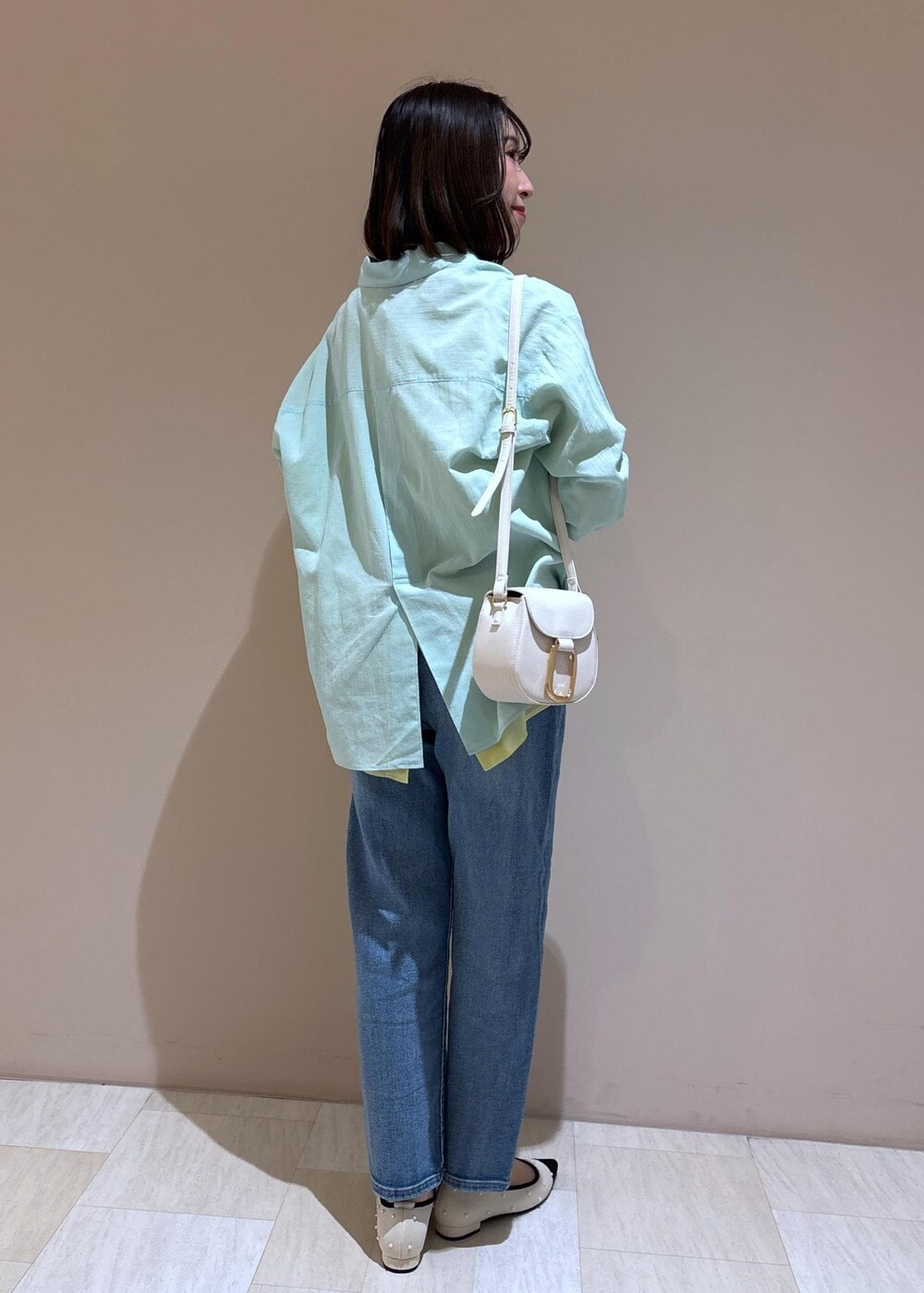 ホワイト系のショルダーバッグ、ブルー系のデニムパンツ、グリーン系のシャツ/ブラウスを着用したレディースの冬コーディネートの4枚目の写真