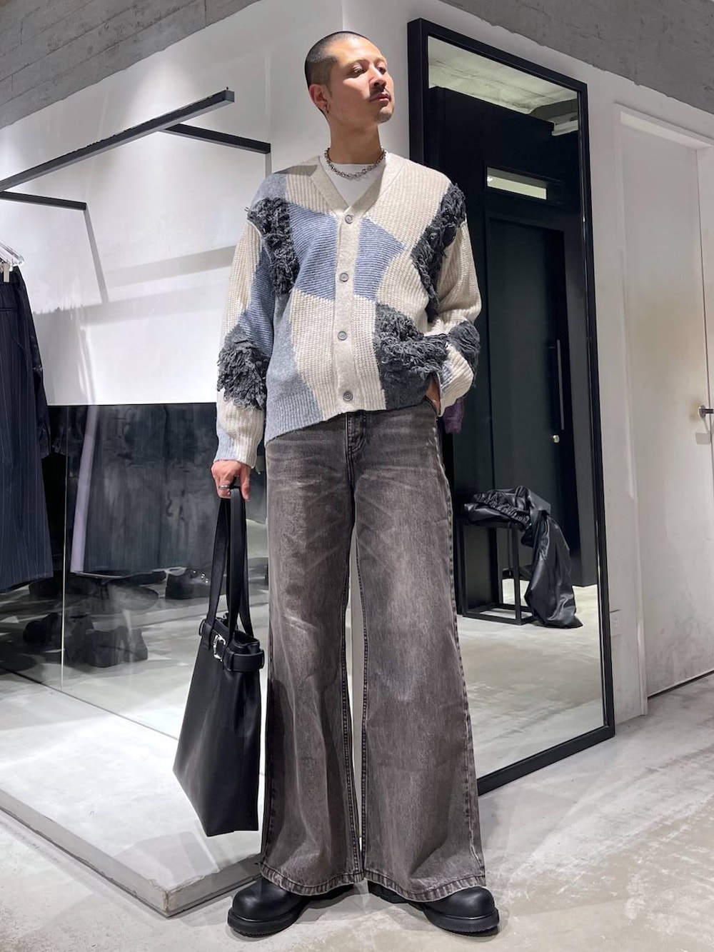 ブラック系のブルゾン、ブラック系のトートバッグ、ブラウン系のデニムパンツを着用したメンズの冬コーディネートの5枚目の写真