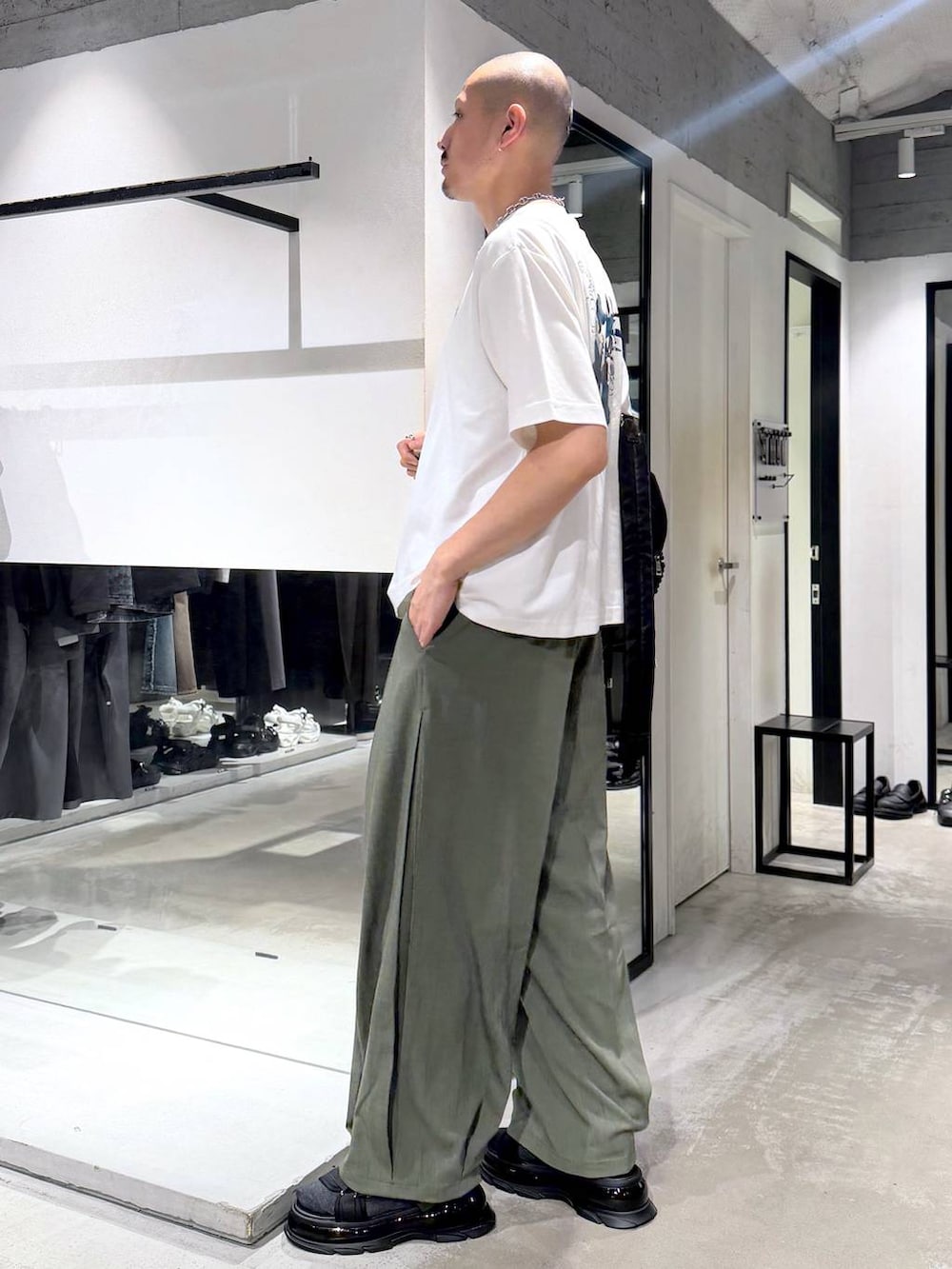 ブラック系のサンダル、グリーン系のスラックス、ホワイト系のTシャツ/カットソーを着用したメンズの夏コーディネートの2枚目の写真