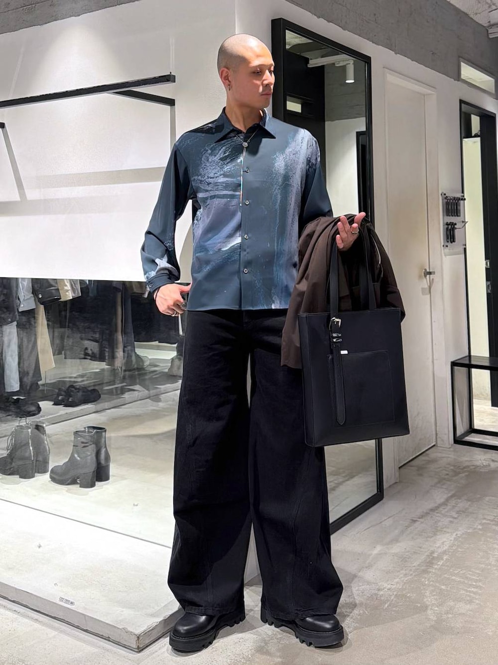 ブラック系のデニムパンツ、ブラック系のドレスシューズ、ブラック系のトートバッグを着用したメンズの冬コーディネートの5枚目の写真