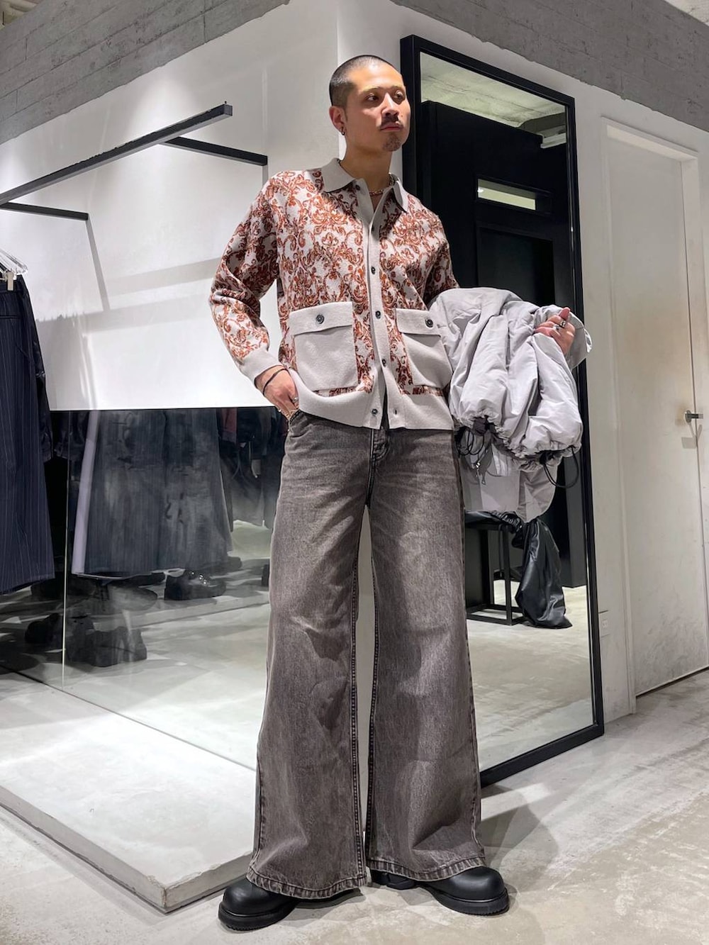 グレー系のダウンジャケット/コート、ブラウン系のデニムパンツ、ブラック系のドレスシューズを着用したメンズの冬コーディネートの5枚目の写真