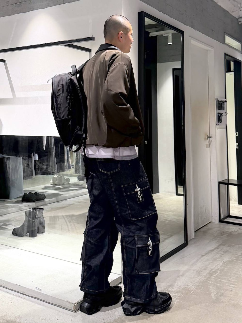 ブラック系のスニーカー、ブラウン系のブルゾン、ブラック系のバックパック/リュックを着用したメンズの春コーディネートの3枚目の写真
