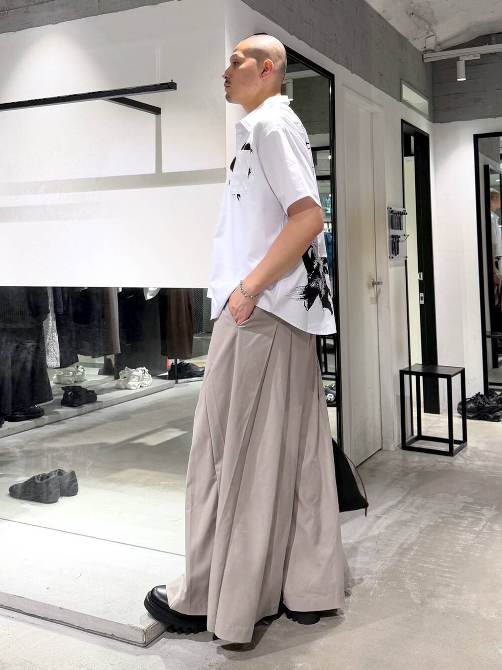 ブラック系のドレスシューズ、ブラック系のトートバッグ、ベージュ系のスラックスを着用したメンズの夏コーディネートの2枚目の写真