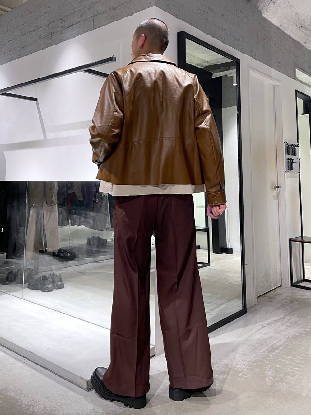 レッド系のスラックス、ブラック系のドレスシューズ、ブラック系のニット/セーターを着用したメンズの冬コーディネートの3枚目の写真