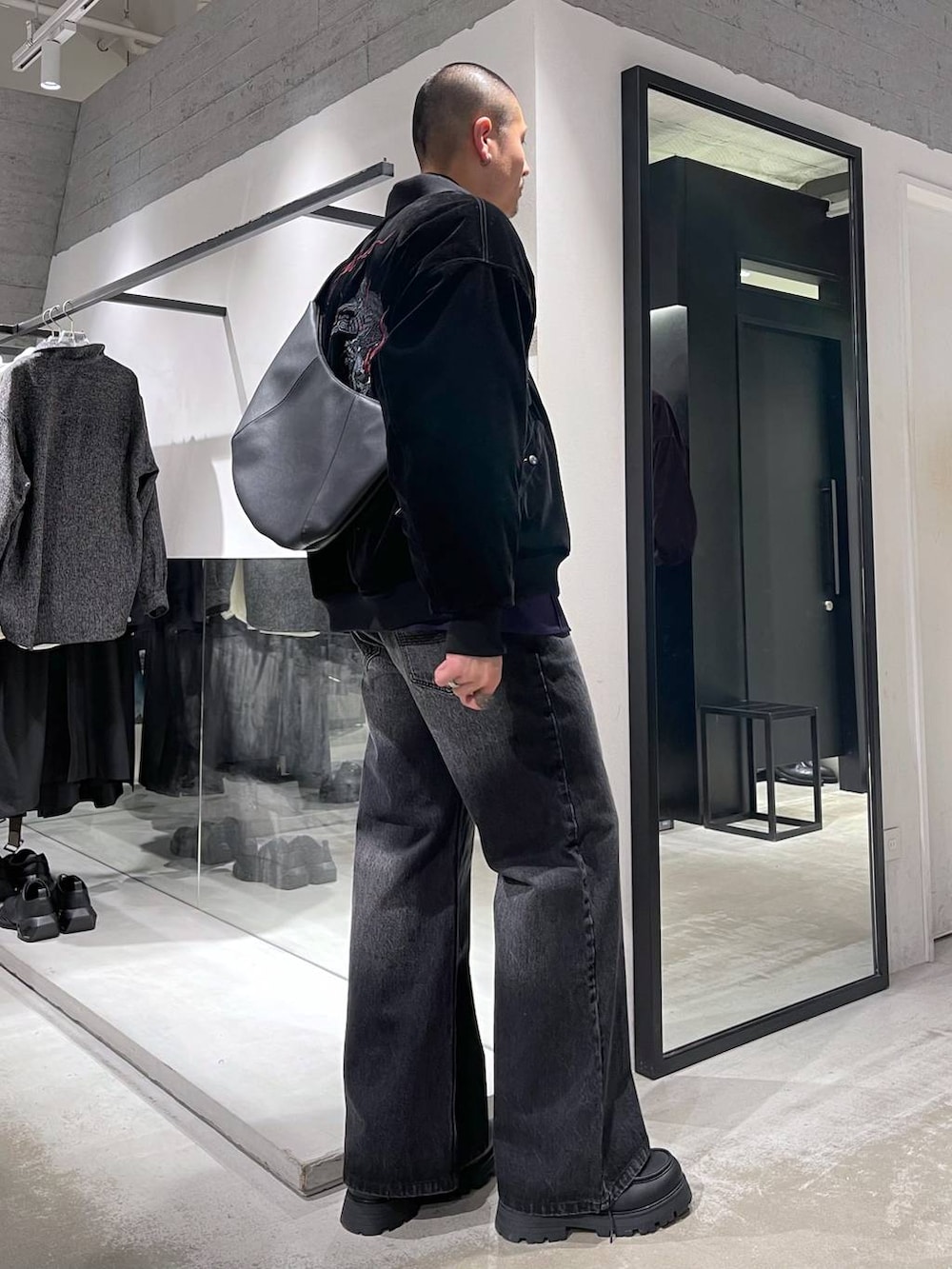 ブラック系のデニムパンツ、ブラック系のドレスシューズ、ブラック系のショルダーバッグを着用したメンズの冬コーディネートの4枚目の写真