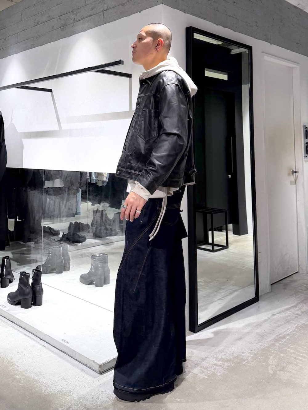 グレー系のパーカー、ブラック系のドレスシューズ、ブラック系のハンドバッグを着用したメンズの冬コーディネートの2枚目の写真