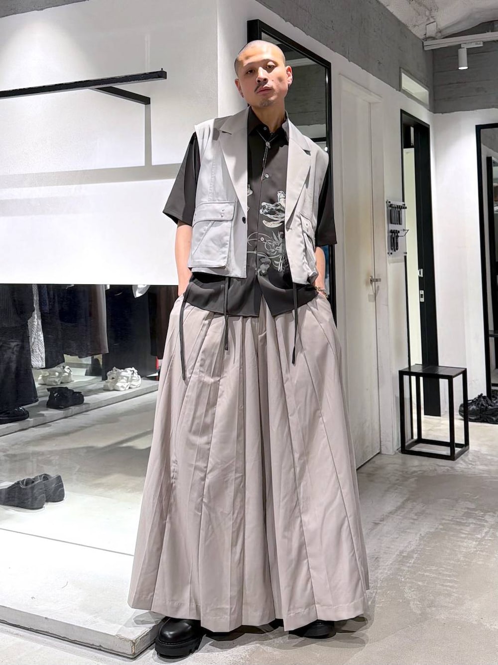 ブラック系のドレスシューズ、グレー系のベスト、ベージュ系のスラックスを着用したメンズの夏コーディネートの2枚目の写真