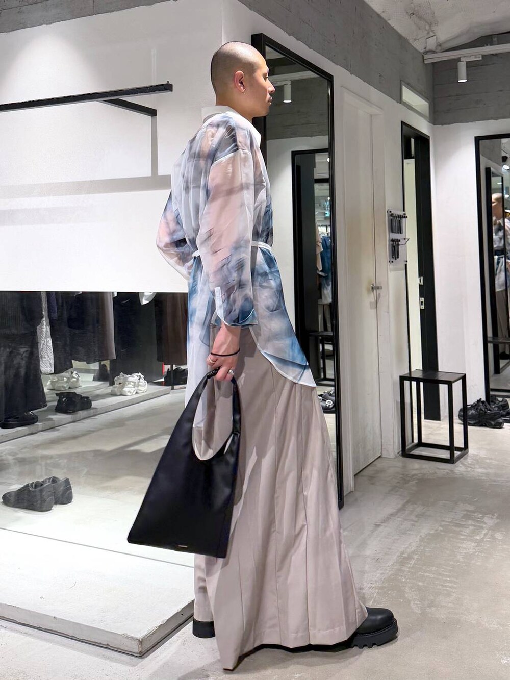 ブラック系のトートバッグ、ブラック系のドレスシューズ、ベージュ系のスラックスを着用したメンズの春コーディネートの4枚目の写真