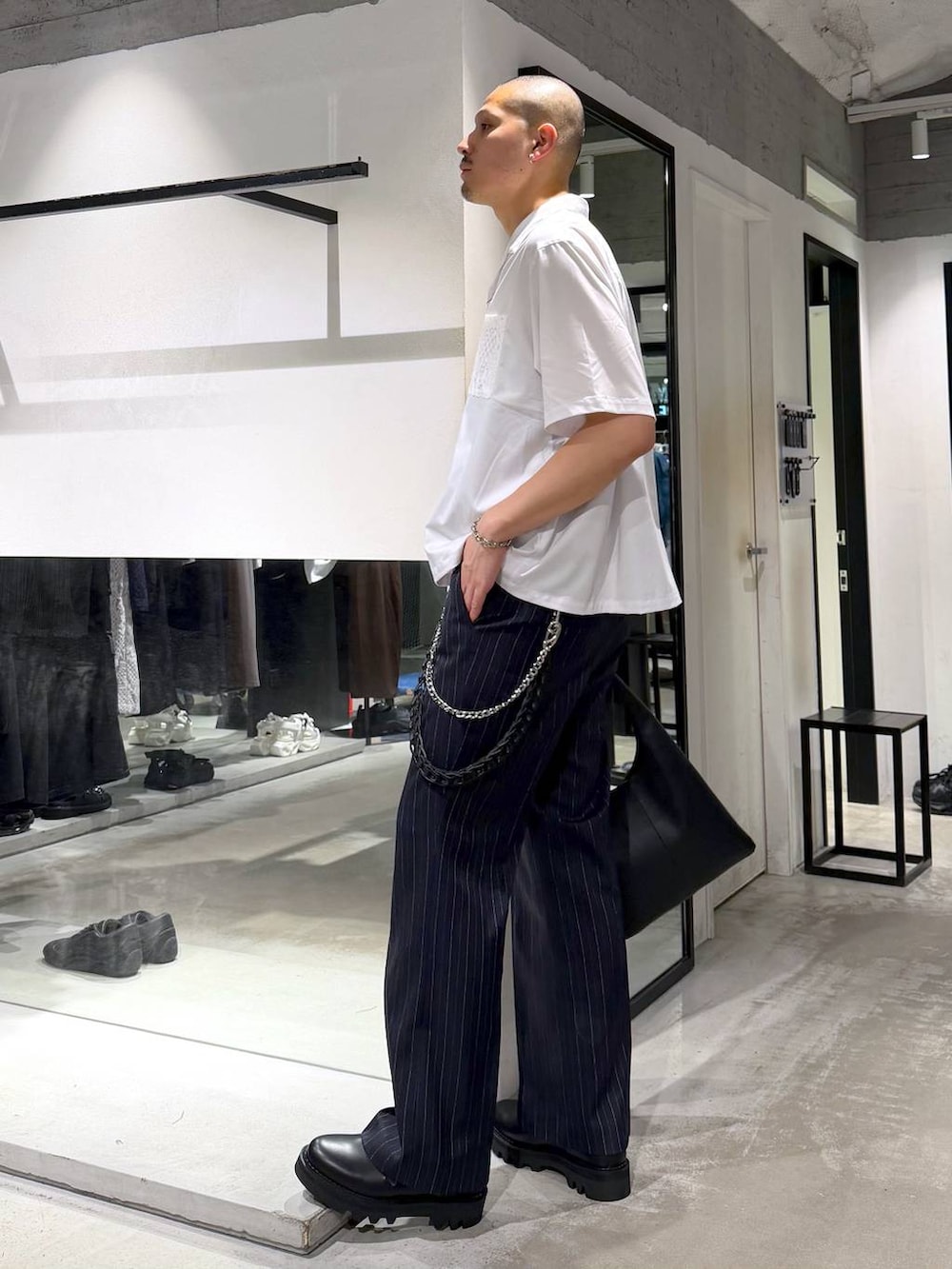 ブラック系のトートバッグ、ブルー系のスラックス、ブラック系のドレスシューズを着用したメンズの春コーディネートの2枚目の写真