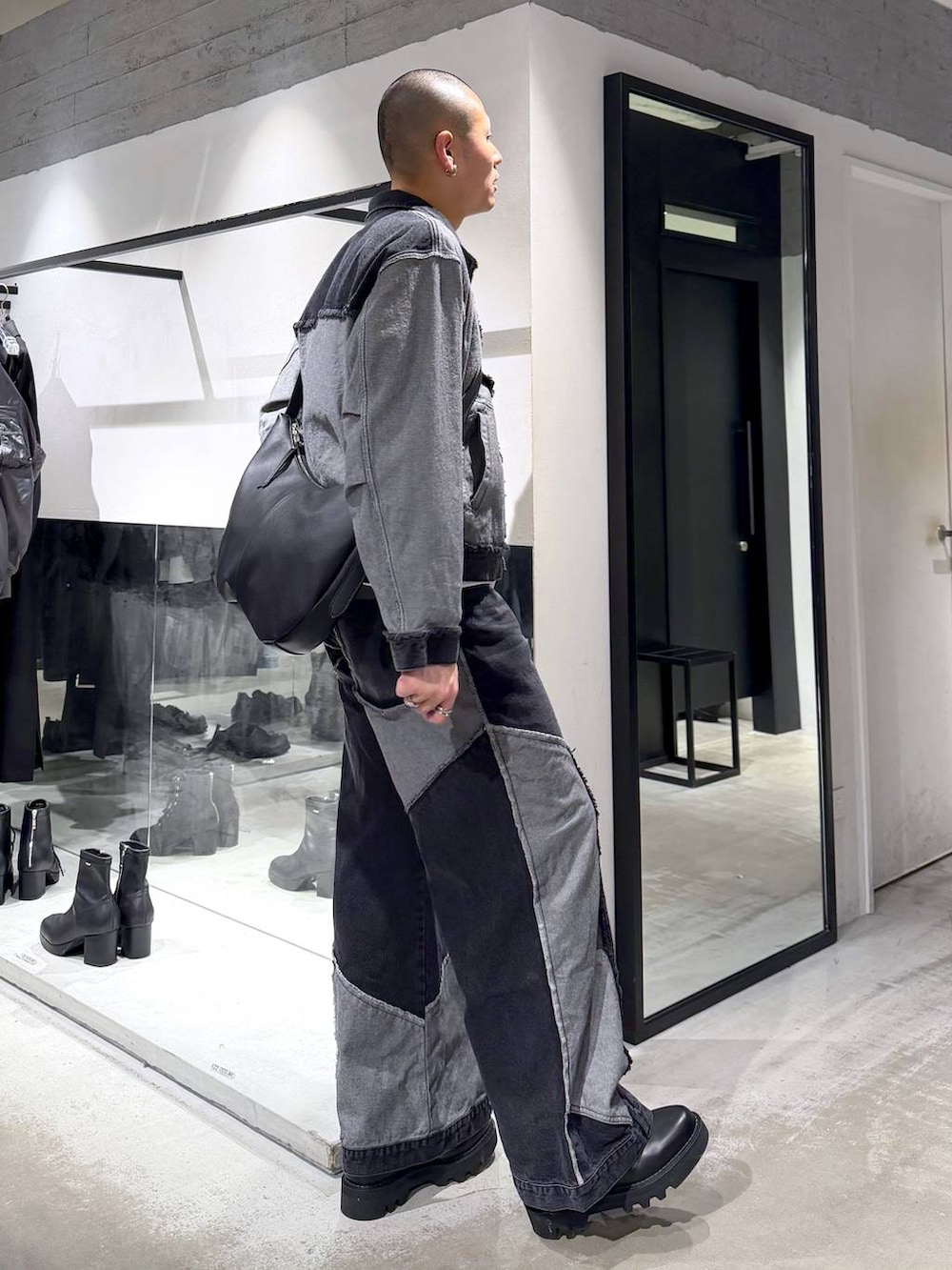 ブラック系のデニムパンツ、ブラック系のドレスシューズ、ブラック系のショルダーバッグを着用したメンズの冬コーディネートの4枚目の写真