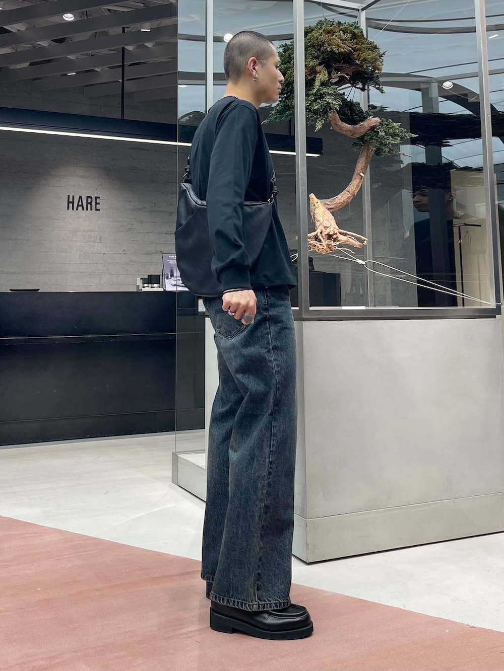 ブラック系のローファー、ブルー系のデニムパンツ、ブラック系のショルダーバッグを着用したメンズの秋コーディネートの4枚目の写真