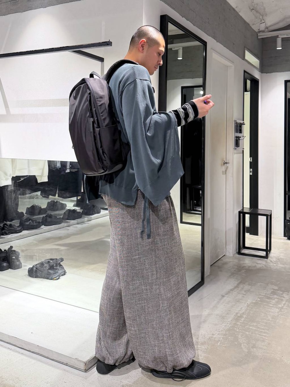 ブラック系のバックパック/リュック、グレー系のスラックス、グリーン系のカーディガン/ボレロを着用したメンズの春コーディネートの5枚目の写真