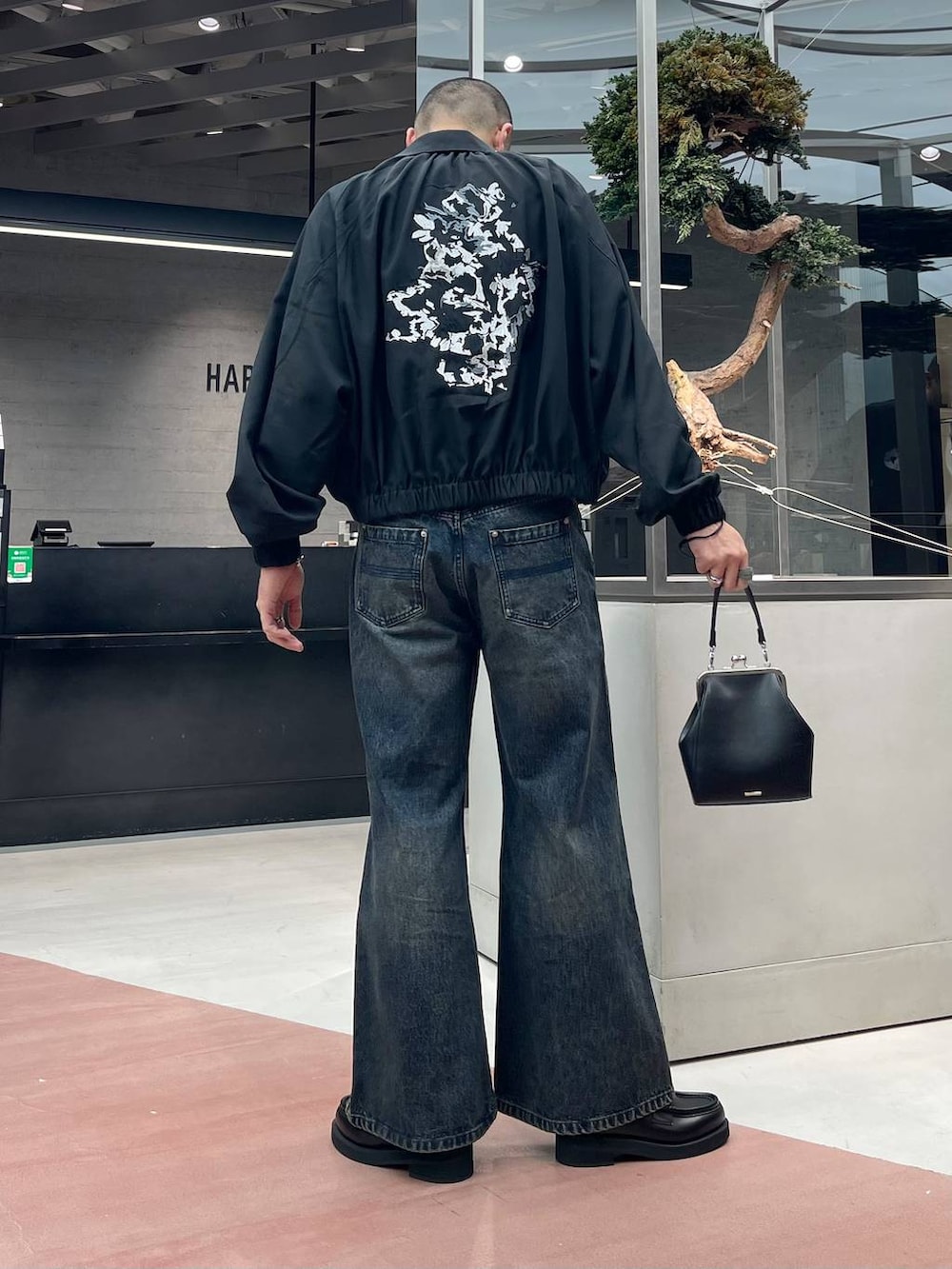 ブラック系のローファー、ブルー系のデニムパンツ、ブラック系のショルダーバッグを着用したメンズの秋コーディネートの3枚目の写真