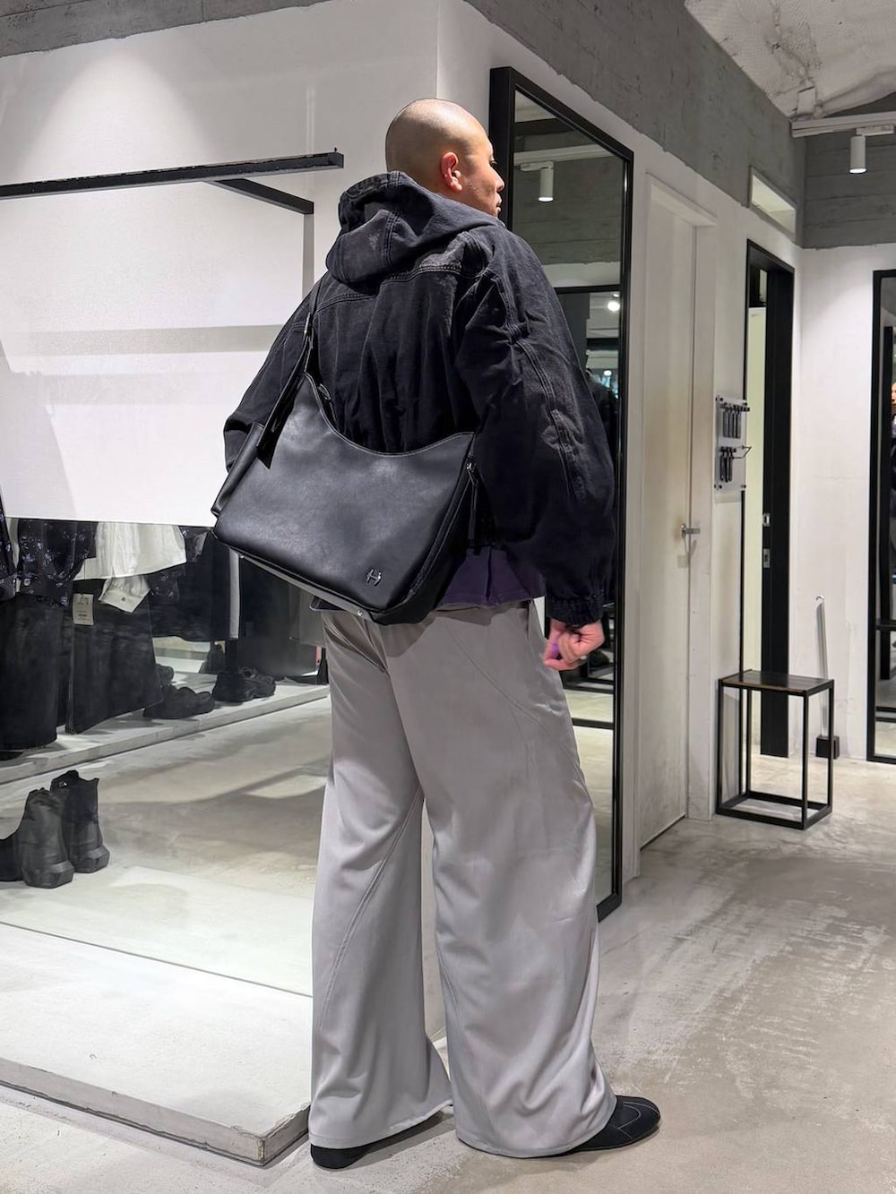 ブラック系のブルゾン、グレー系のスラックス、ブラック系のショルダーバッグを着用したメンズの春コーディネートの4枚目の写真