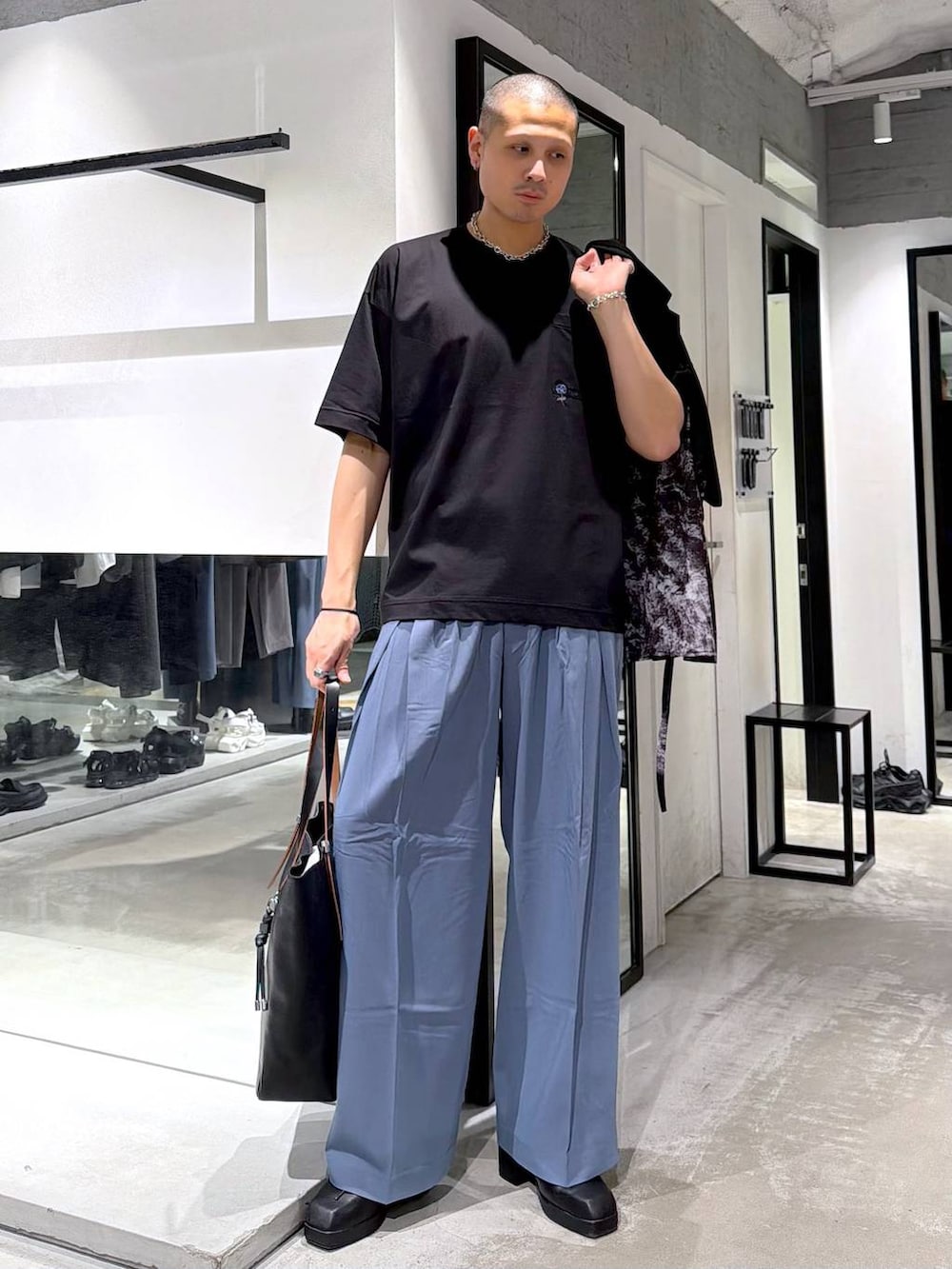 ブラック系のTシャツ/カットソー、ブラック系のサンダル、ブルー系のスラックスを着用したメンズの春コーディネートの6枚目の写真