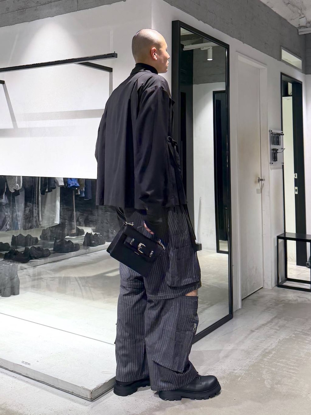 ブラック系のハンドバッグ、ブラック系のドレスシューズ、グレー系のカーゴパンツを着用したメンズの冬コーディネートの5枚目の写真